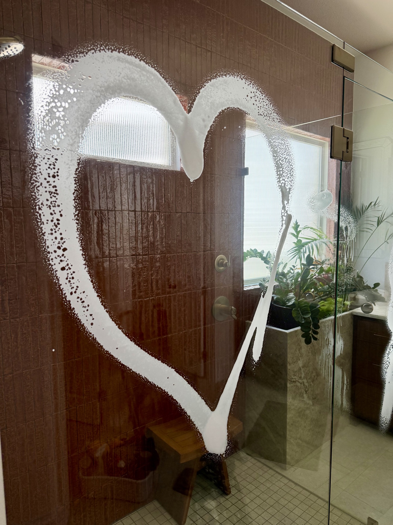 A freshly cleaned glass shower decorated with a heart